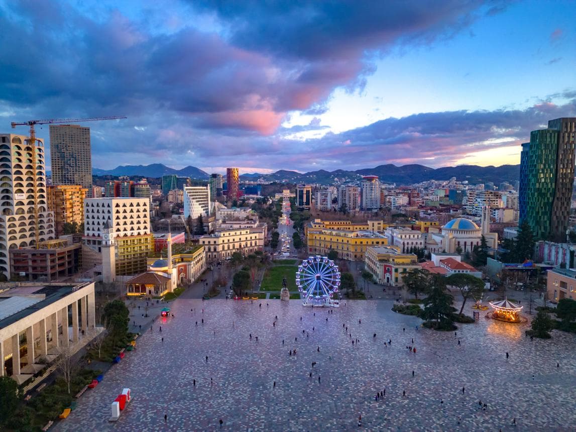 Tirana's Skanderbeg Square at sunset with the city's modern architecture and ferris wheel
